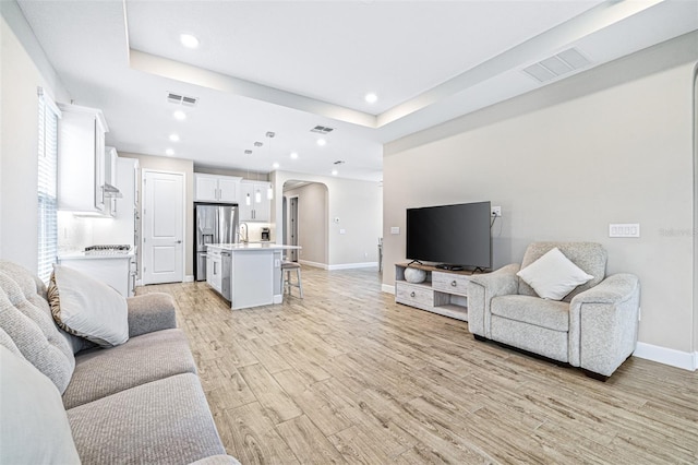 living room with a tray ceiling and light hardwood / wood-style flooring