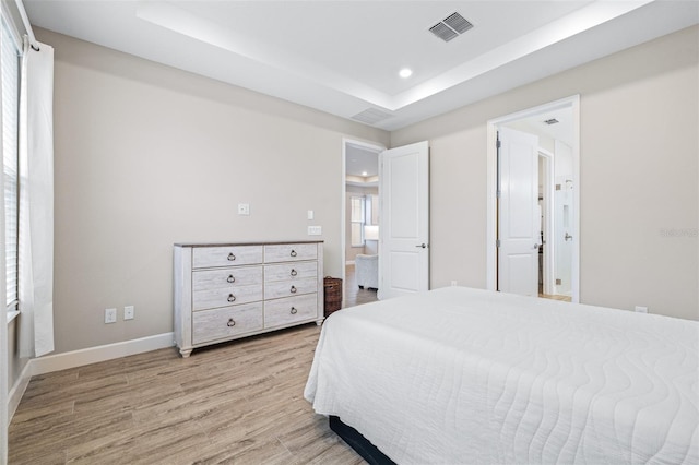 bedroom featuring a raised ceiling and light hardwood / wood-style flooring