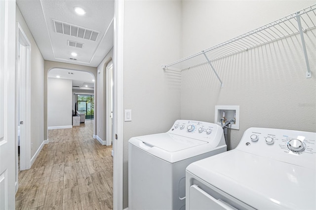 laundry area with washer and clothes dryer and light wood-type flooring