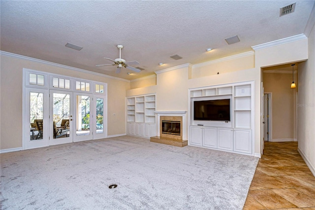 unfurnished living room with built in features, ceiling fan, a high end fireplace, crown molding, and a textured ceiling