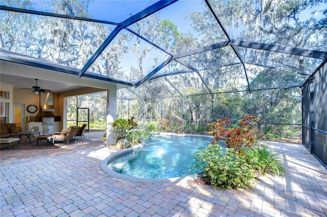 view of swimming pool featuring ceiling fan, outdoor lounge area, a patio area, and glass enclosure