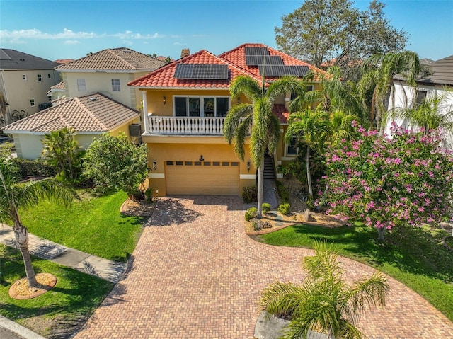 mediterranean / spanish-style house with a garage, stucco siding, a tile roof, decorative driveway, and a front yard