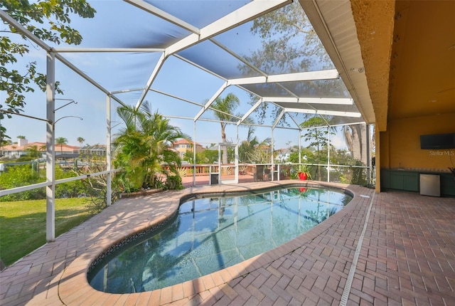 outdoor pool featuring glass enclosure and a patio area