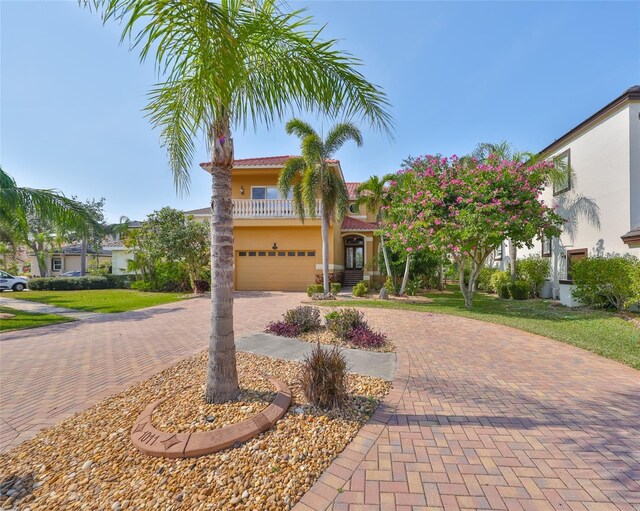 view of front of property with decorative driveway, an attached garage, a front lawn, and stucco siding