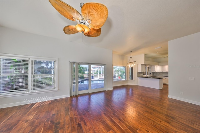 unfurnished living room with ceiling fan, baseboards, and dark wood-style flooring