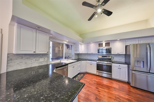 kitchen with a sink, white cabinets, appliances with stainless steel finishes, backsplash, and dark wood-style floors