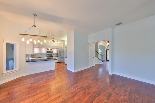 kitchen with visible vents, dark countertops, open floor plan, stainless steel appliances, and backsplash