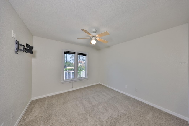 carpeted empty room with ceiling fan, baseboards, and a textured ceiling