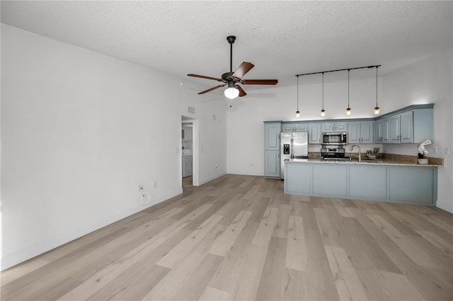 kitchen with sink, light wood-type flooring, appliances with stainless steel finishes, kitchen peninsula, and ceiling fan