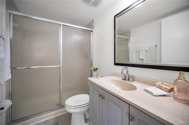 bathroom featuring a shower with door, vanity, and toilet