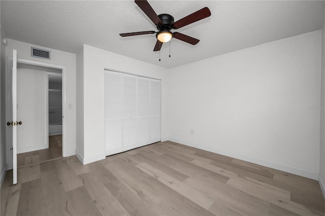 unfurnished bedroom featuring ceiling fan, a textured ceiling, a closet, and light wood-type flooring