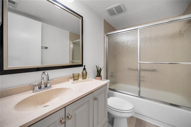 full bathroom featuring vanity, toilet, and bath / shower combo with glass door