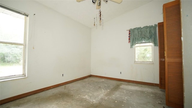 spare room with vaulted ceiling, concrete floors, and ceiling fan