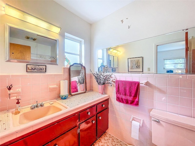 bathroom featuring vanity, toilet, and tile walls