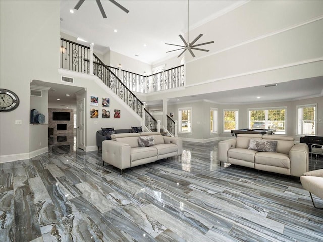 living room featuring a towering ceiling, ornamental molding, and ceiling fan