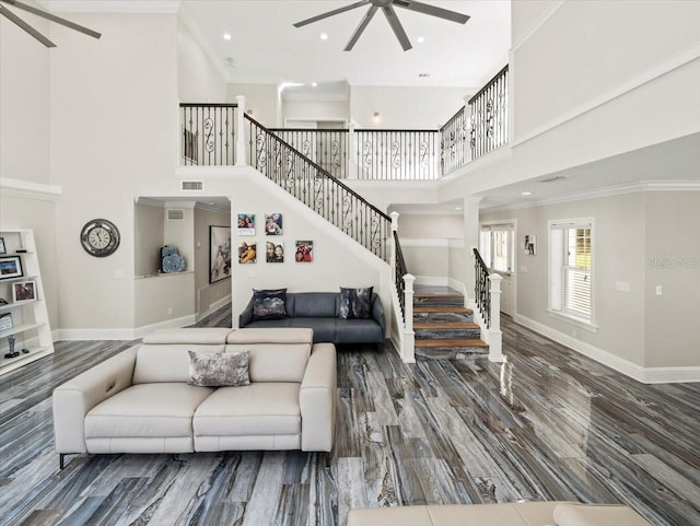 living room with crown molding, ceiling fan, wood-type flooring, and a high ceiling