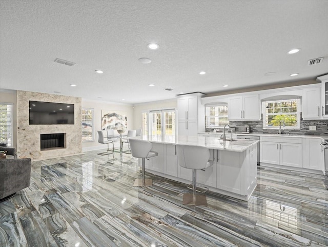 kitchen with white cabinetry, an island with sink, sink, and a kitchen breakfast bar