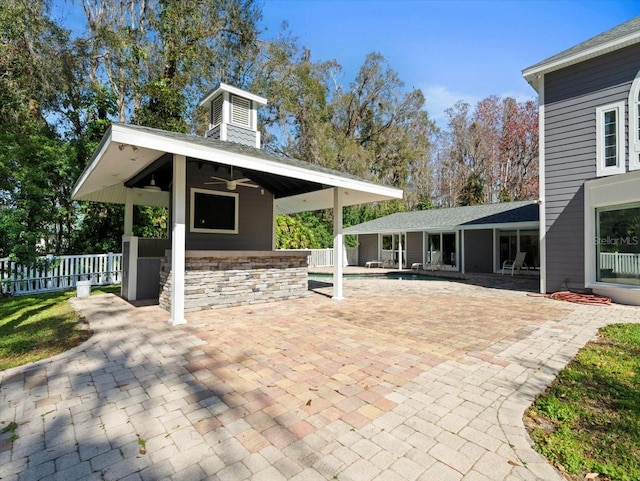 view of patio with ceiling fan, an outdoor structure, and a fenced in pool