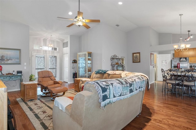 living room with french doors, ceiling fan with notable chandelier, high vaulted ceiling, and light hardwood / wood-style flooring