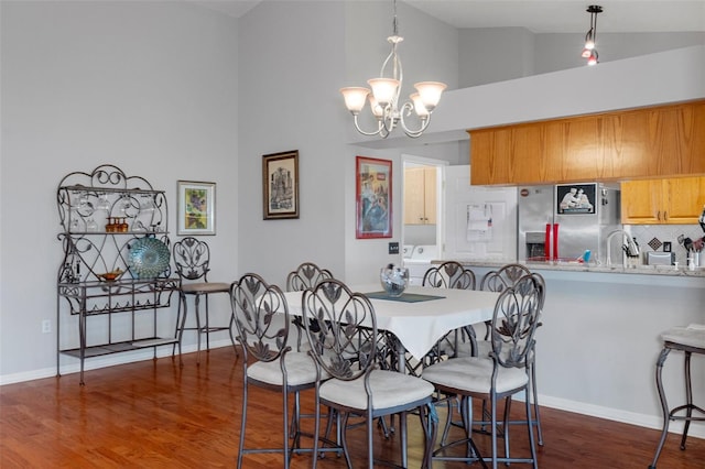 dining space with dark wood-type flooring, a notable chandelier, and high vaulted ceiling