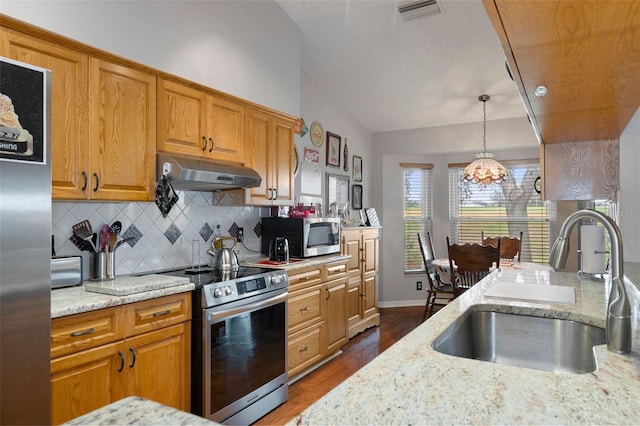 kitchen with light stone counters, stainless steel appliances, vaulted ceiling, and sink