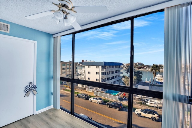 sunroom featuring ceiling fan and a water view