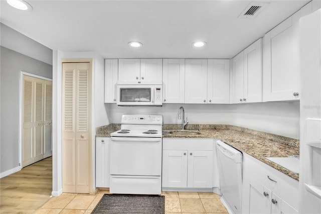 kitchen with sink, white cabinets, light tile patterned floors, light stone countertops, and white appliances