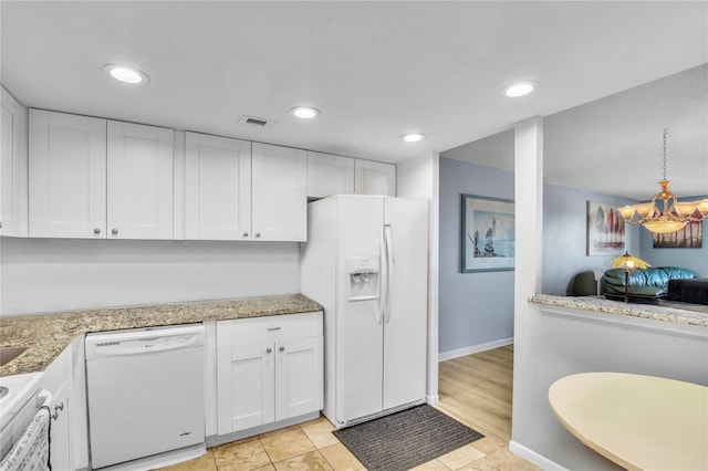 kitchen with light stone counters, white cabinets, white appliances, and decorative light fixtures