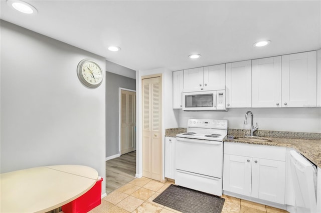 kitchen with white appliances, light stone countertops, sink, and white cabinets