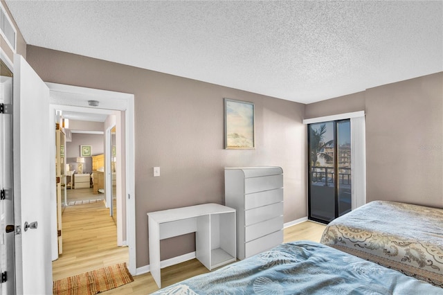 bedroom with access to exterior, a textured ceiling, and light wood-type flooring