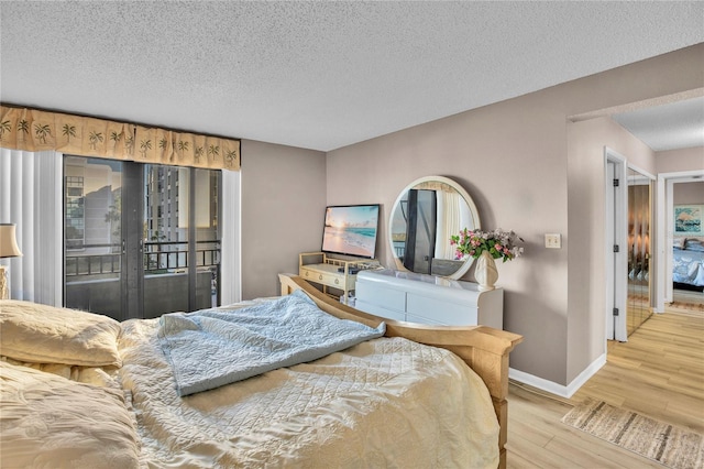 bedroom with hardwood / wood-style floors, access to outside, and a textured ceiling