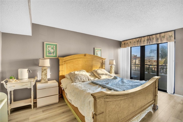 bedroom featuring access to exterior, light hardwood / wood-style flooring, and a textured ceiling