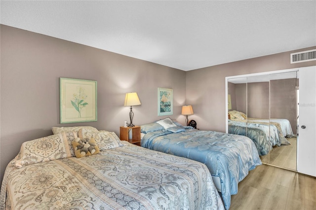 bedroom with light hardwood / wood-style floors and a closet