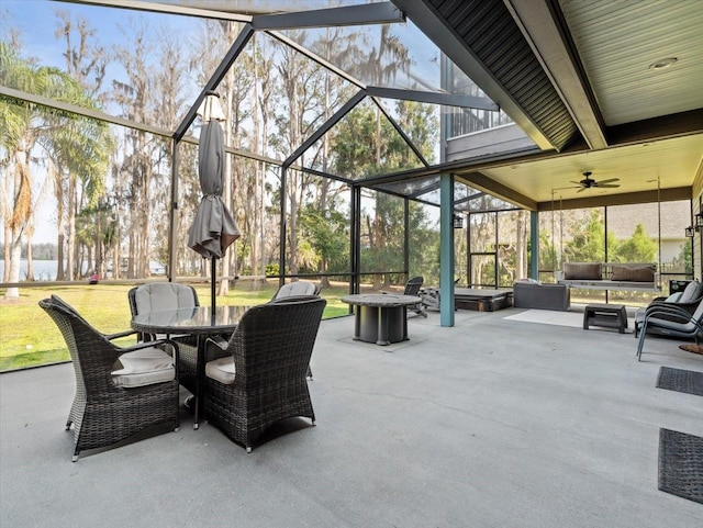 view of patio featuring ceiling fan, glass enclosure, and an outdoor fire pit