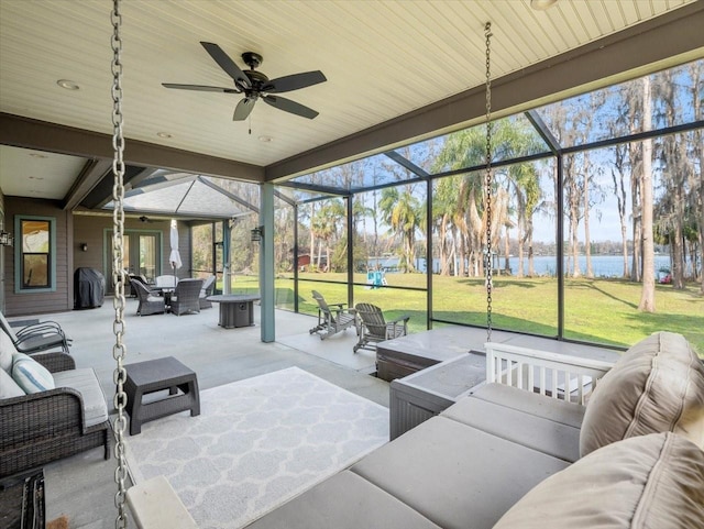 view of patio featuring a water view, ceiling fan, an outdoor living space, and glass enclosure