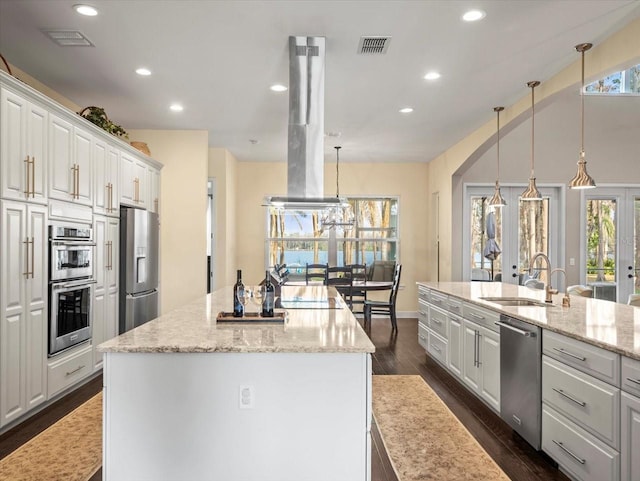 kitchen with white cabinetry, appliances with stainless steel finishes, a center island, and decorative light fixtures