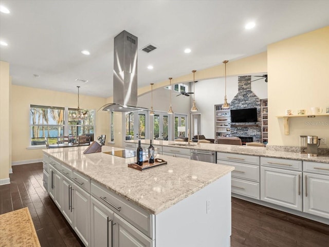 kitchen featuring ceiling fan, light stone countertops, white cabinets, island exhaust hood, and decorative light fixtures