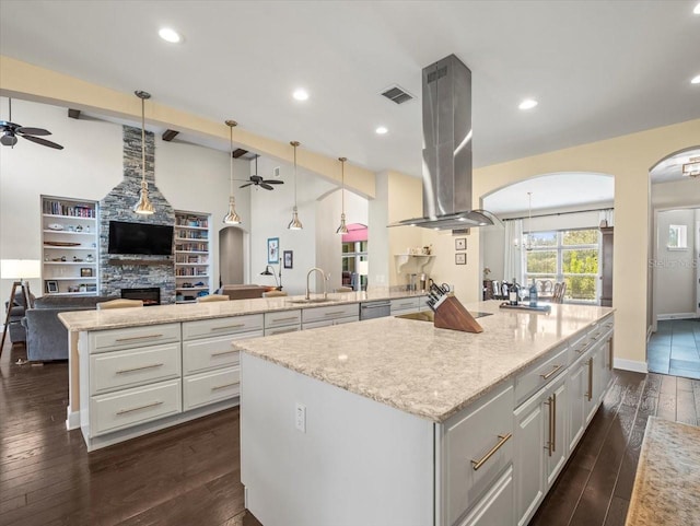 kitchen with pendant lighting, a spacious island, island range hood, light stone countertops, and kitchen peninsula