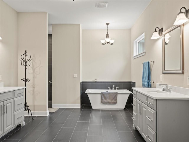 bathroom with vanity, a bath, tile patterned flooring, and a chandelier