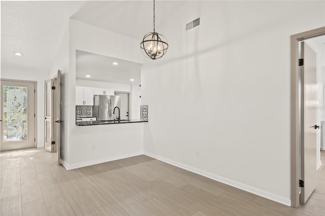 unfurnished dining area featuring a notable chandelier and light wood-type flooring