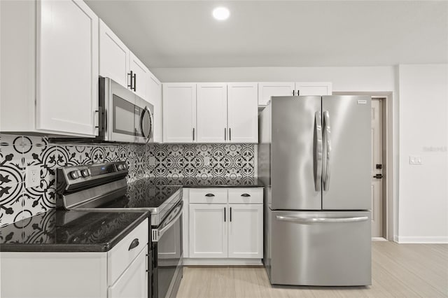 kitchen with tasteful backsplash, white cabinets, and appliances with stainless steel finishes