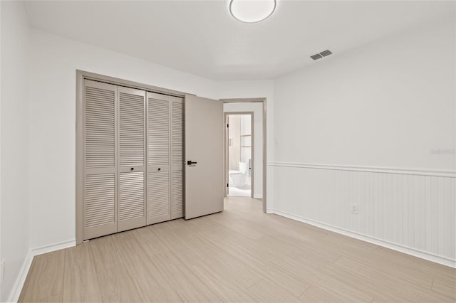 unfurnished bedroom featuring a closet and light wood-type flooring