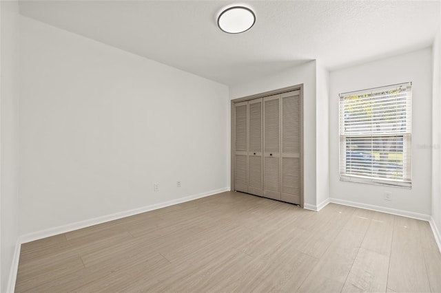 unfurnished bedroom featuring a closet, light hardwood / wood-style flooring, and a textured ceiling