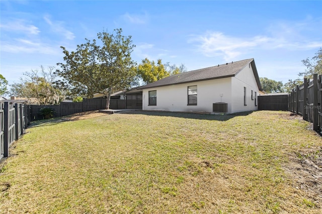 rear view of property featuring a lawn and central air condition unit