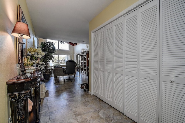 hallway with lofted ceiling and light tile patterned floors