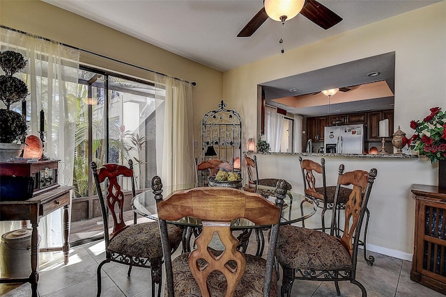 tiled dining area featuring ceiling fan and sink