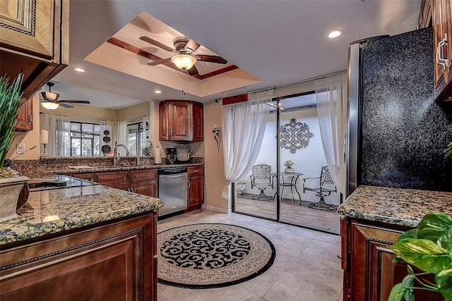 kitchen featuring sink, light tile patterned floors, stainless steel appliances, a raised ceiling, and dark stone counters