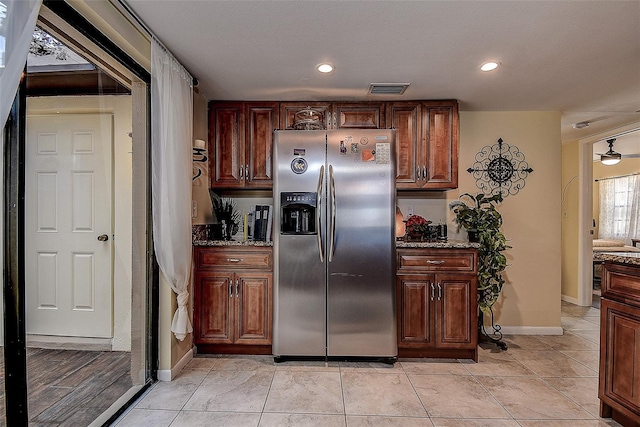 kitchen with stainless steel refrigerator with ice dispenser, stone countertops, and light tile patterned flooring