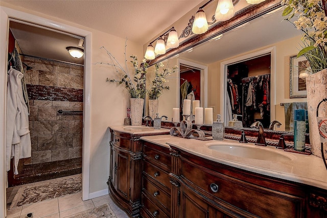 bathroom featuring vanity, a tile shower, tile patterned floors, and a textured ceiling