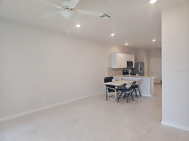 kitchen with stainless steel refrigerator with ice dispenser, a breakfast bar, sink, white cabinetry, and ceiling fan